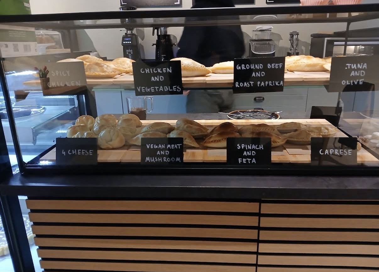 The empanada case — every flavor labelled in chalk