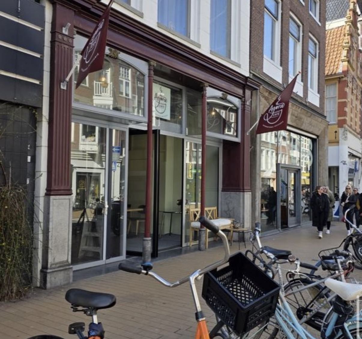 Agora Café storefront on Oude Ebbingestraat, oxblood facade and flags