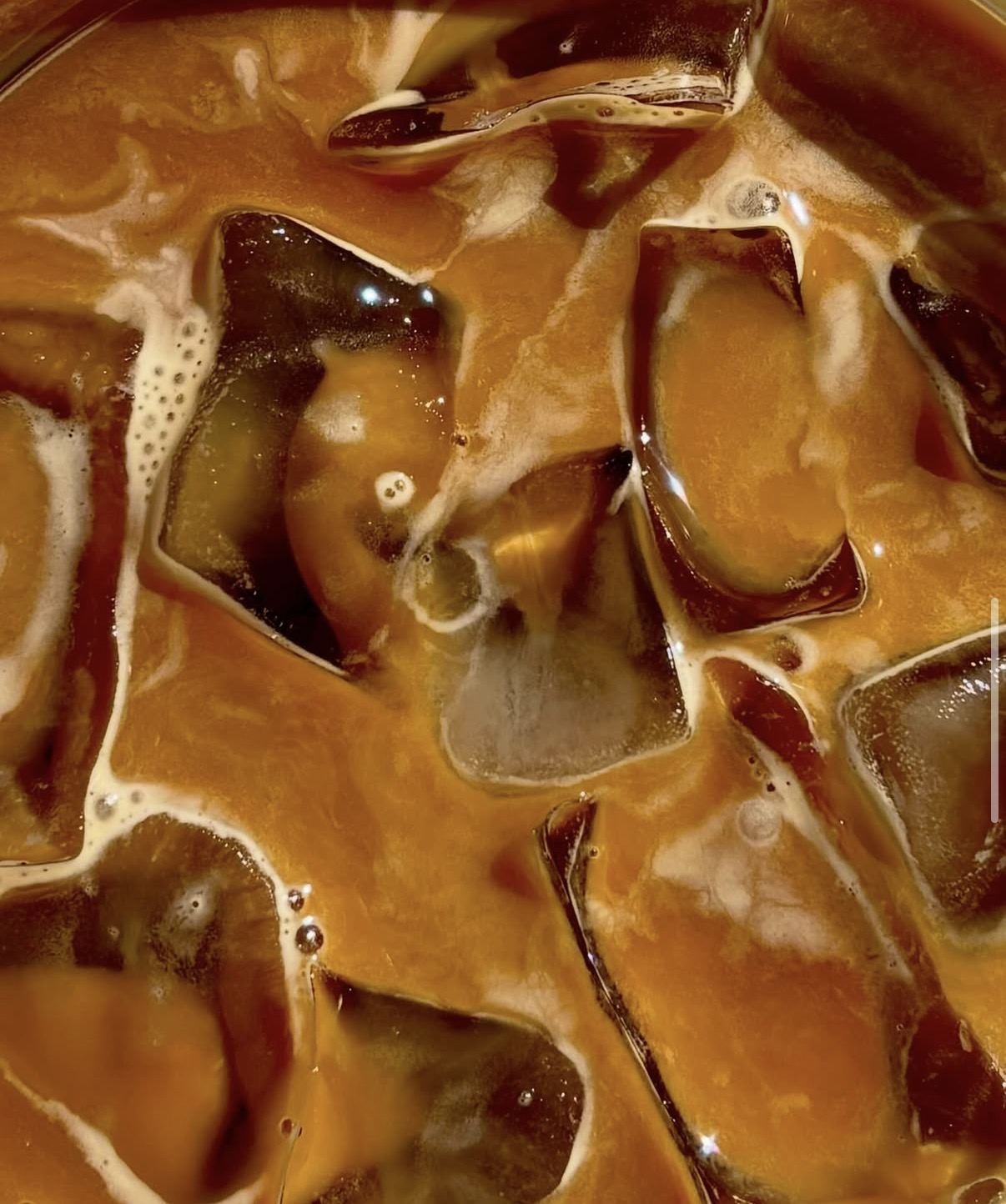 Close-up of a freddo espresso — ice, crema and amber light